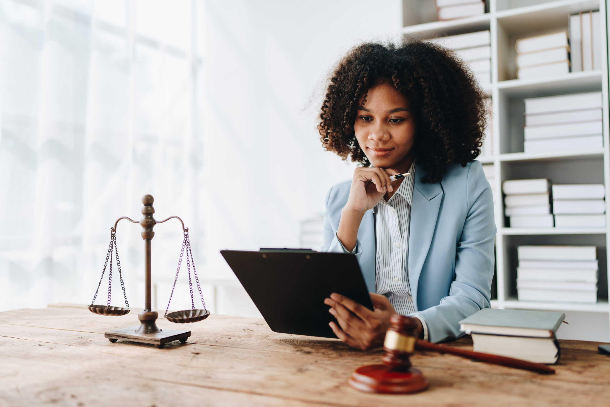 African American lawyer reviewing legal documents and scales of justice, car accident claim expertise.
