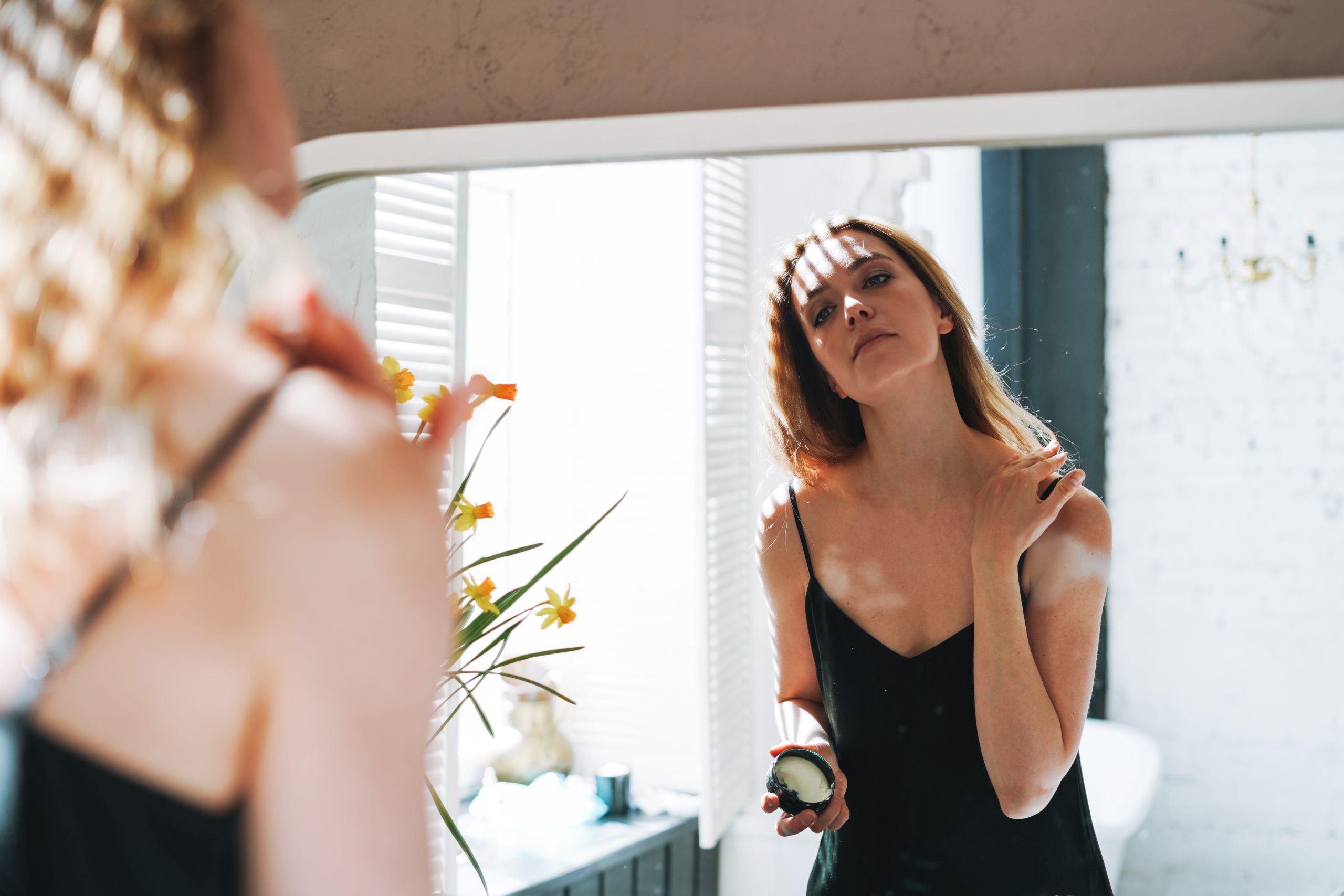 Woman applying body cream, celebrating achievement and self-reward.